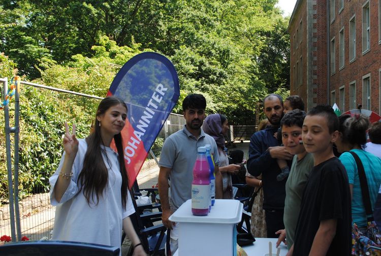 Sommerfest 2025 An einem Stand der Johanniter unterhält sich eine kleine Menschengruppe.