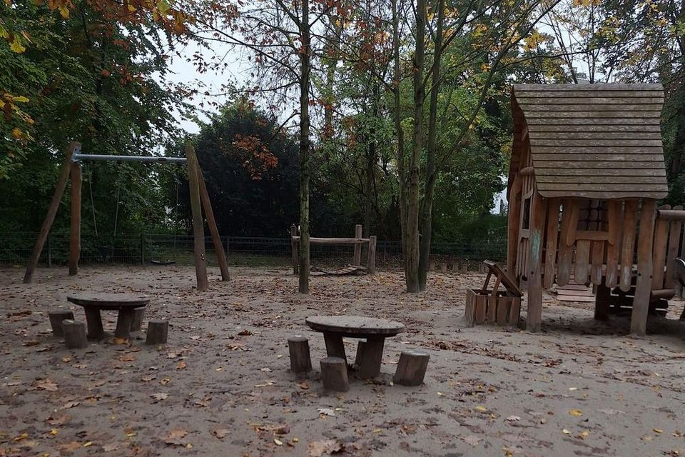 Spielplatz einer Krippe: Es gibt Schaukeln, eine kleine Brücke und Sitzgruppen.