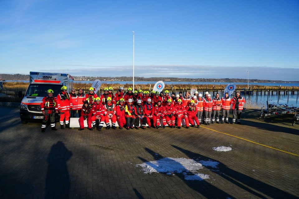 Gruppenfoto mit rund 50 Rotkreuzler*innen in orangefarbener Einsatzkleidung.