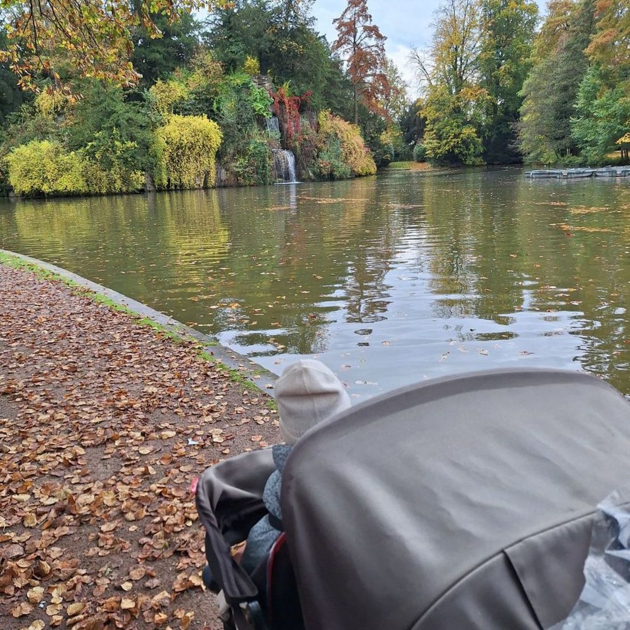 Blick über einen Kinderwagen auf einen großen Teich.