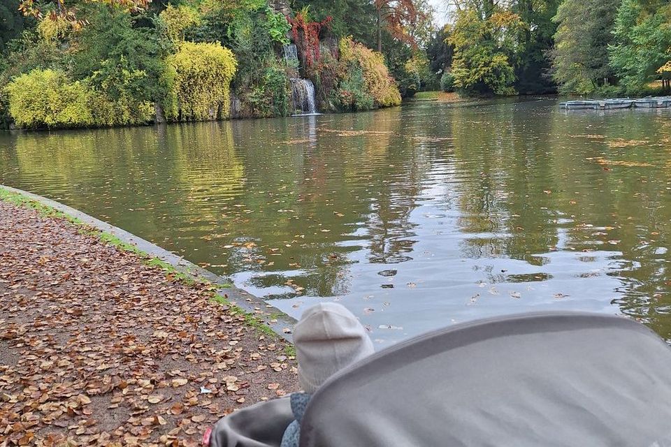 Blick über einen Kinderwagen auf einen großen Teich.